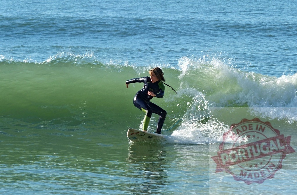 Young surfer riding ocean wave on surfboard | Young person in wetsuit balancing on surfboard while surfing a green ocean wave - Realisiert mit Pictrs.com