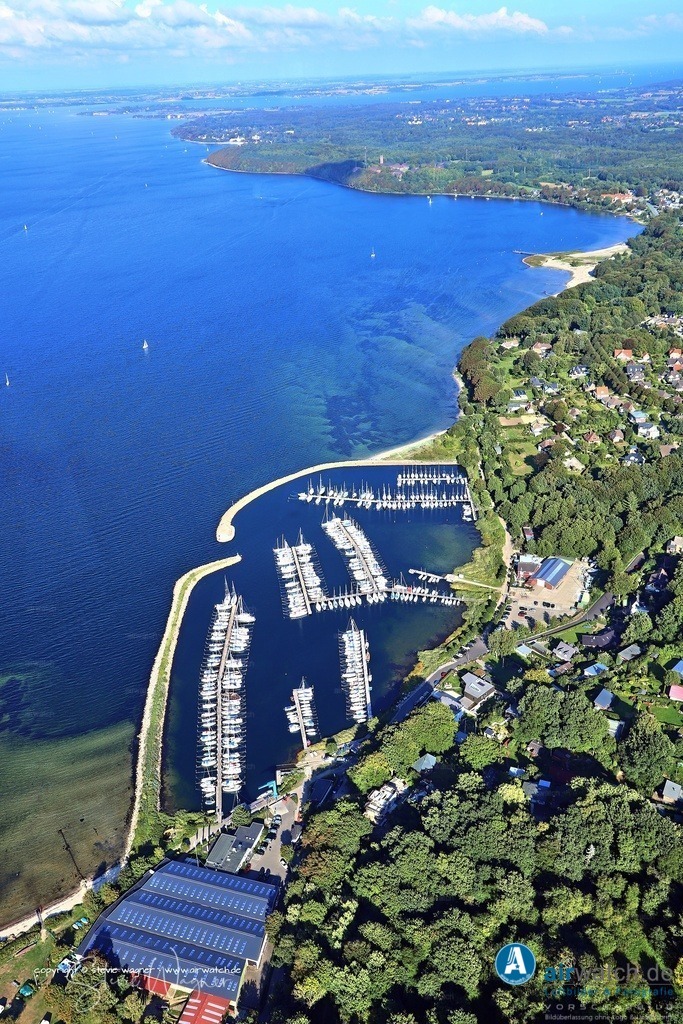 Die Lage des Hafens bietet einen unverbauten Blick auf die Flensburger Förde - Luftbild Yachthafen Fahrensodde | Im Jahr 2021 wurde die Krananlage im Hafen erneuert, und eine neue Winterlagerhalle wurde errichtet. Zudem wurden im Mai 2024 die Schäden der Sturmflut beseitigt und das WLAN verbessert. Die Lage des Hafens bietet einen unverbauten Blick auf die Flensburger Förde und die dänische Küste, was durch die Hanglage und die Bepflanzung des Grundstücks zusätzlich gefördert wird.