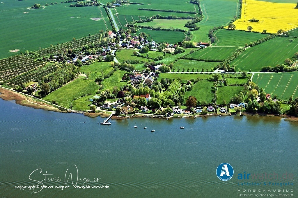 Luftbild Ostseefjord Schlei, Sieseby, Gasthof Alt Sieseby, | Die älteste Baustruktur im Ort ist die romanische Feldsteinkirche, die im Kern bereits im 12. Jahrhundert errichtet wurde und als das älteste Bauwerk der Gemeinde gilt. Sie wurde im 13. Jahrhundert erweitert, wobei ein weiterer Chor nach Osten hin angebaut und ein Kreuzrippengewölbe eingezogen wurde. In einer Urkunde vom 15. August 1267 wird erstmals die Existenz eines Kirchspiels in Sieseby erwähnt. Die Kirche wurde 2015 saniert, wobei der Dachstuhl erneuert und das Gewölbe restauriert wurde.