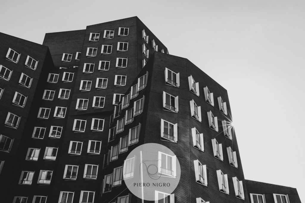 Gehry Bauten Düsseldorf - Wanddeko | Wallart | Fotokunst | Discover the masterpiece of modern architecture with our exclusive wall art of the Gehry Buildings in Düsseldorf. This breathtaking piece captures the unique dynamism and futuristic elegance of the famous buildings designed by the globally renowned architect Frank Gehry. Perfect for lovers of contemporary architecture or for those who want to make a statement in their living or office space. The image presents one of the three units comprising the Gehry Buildings that dominate the Düsseldorf skyline. In black and white and with razor-sharp resolution, this wall art is essential for collectors and an inspiring addition to any interior decor. Bring a piece of architectural history into your home and enjoy the beauty and design of the Gehry Buildings every day.

Entdecken Sie das Meisterwerk der modernen Architektur mit unserem exklusiven Wandkunstbild der Gehry-Bauten in Düsseldorf. Dieses atemberaubende Stück fängt die einzigartige Dynamik und futuristische Eleganz der berühmten Gebäude ein, die von dem weltweit renommierten Architekten Frank Gehry entworfen wurden. Perfekt für Liebhaber der zeitgenössischen Architektur oder für diejenigen, die ein Statement in ihrem Wohn- oder Bürobereich setzen möchten. Das Bild präsentiert eines der aus Drei Einheiten bestehenden Gehry-Bauten, die die Skyline von Düsseldorf prägen. In Schwarzweiß und gestochen scharfer Auflösung ist dieses Wandbild ein Muss für Sammler und eine inspirierende Ergänzung für jede Inneneinrichtung. Holen Sie sich ein Stück Architekturgeschichte nach Hause und genießen Sie die Schönheit und das Design der Gehry-Bauten jeden Tag. - Realisiert mit Pictrs.com