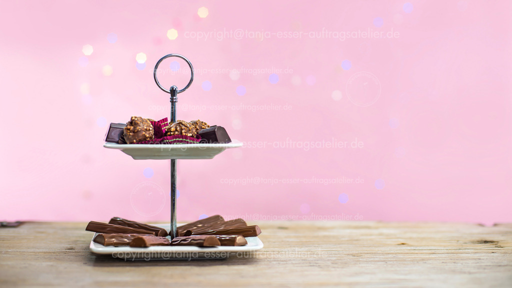 chocolate on a cake stand - copy space | Schokoladen Pralinen auf einer Etagere. Rosa Hintergrund mit Copy Space und buntem Bokeh.