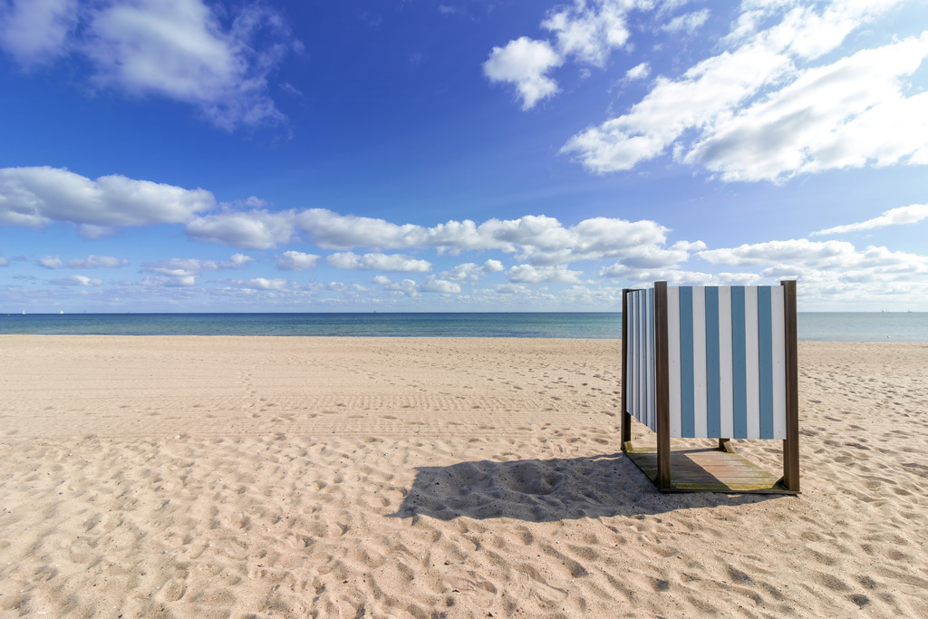 Leinwand: Umkleidekabine am Strand in Weidefeld | Beruhigende Farben und maritime Ruhe – dieses Wandbild bringt die entspannte Atmosphäre des Weidefelder Strandes in den Raum. Die blau-weiß gestreifte Umkleidekabine am Sandstrand verleiht dem Motiv einen freundlichen und harmonischen Akzent, während der offene Himmel mit seinen sommerlichen Wolken eine weitläufige und beruhigende Bildwirkung erzeugt. - Realisiert mit Pictrs.com