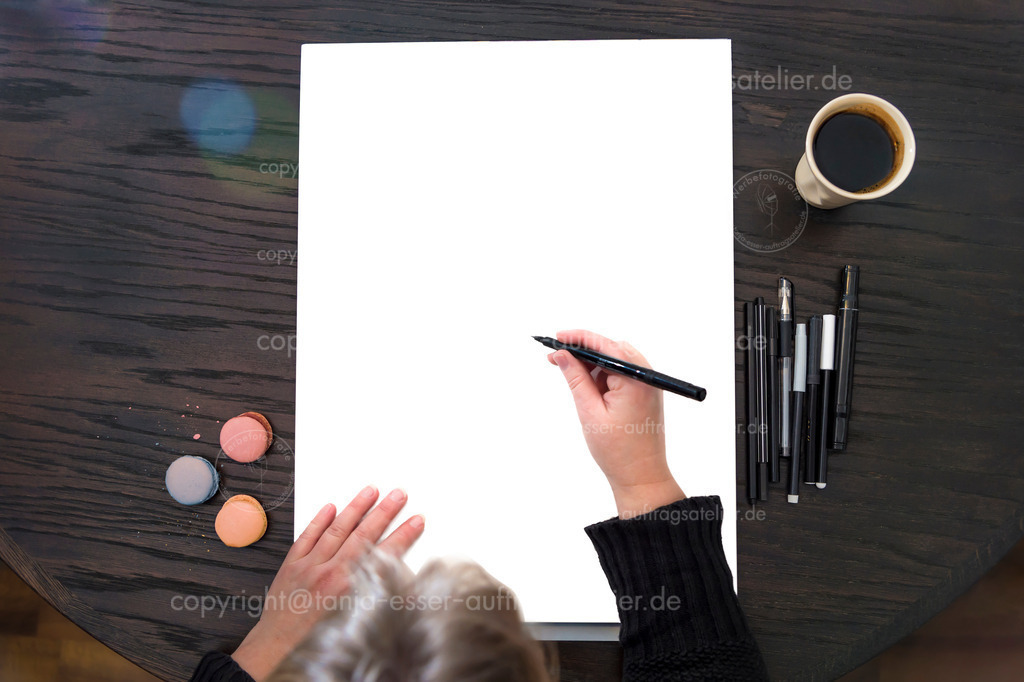 Background for creative pictures - person is starting to draw or write something | Papierblock in Din A 3 bietet viel Copy Space für kreative Projekte. Eine Frau beginnt etwas zu illustrieren oder zu schreiben. Macaroons in bunten Farben und Lens Flares bieten Farbakzente. Mock Up. 