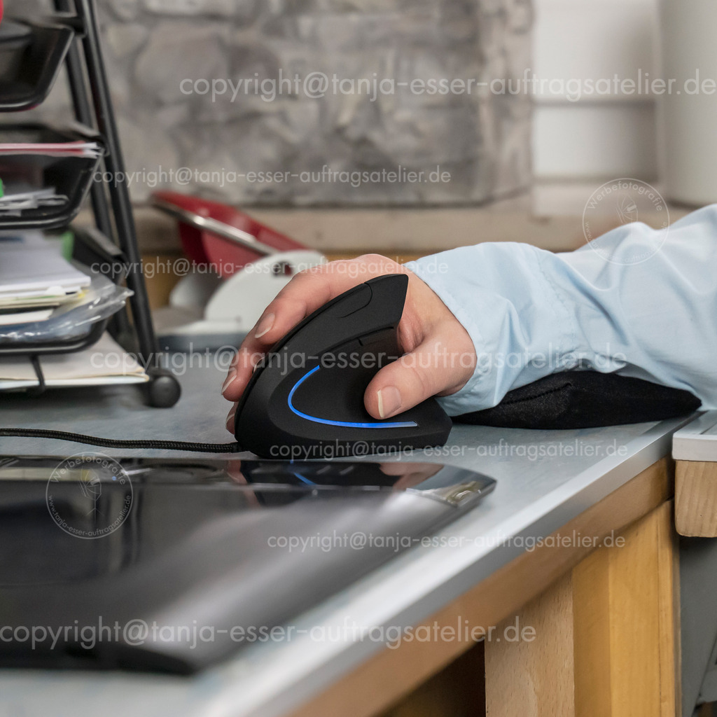 Workstation on the PC with ergonomic mouse | A workplace with a computer. On the desk is a hand in relief position with an ergonomic mouse. In addition to the vertical mouse, a small pillow supports the wrist. Health prevention.