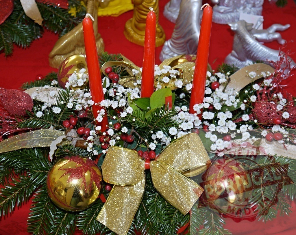 Christmas centerpiece with red candles, gold ribbon, and ornaments creating festive atmosphere | Christmas centerpiece featuring red candles, gold ribbon, and ornaments, evoking a warm and festive holiday atmosphere - Realized with Pictrs.com