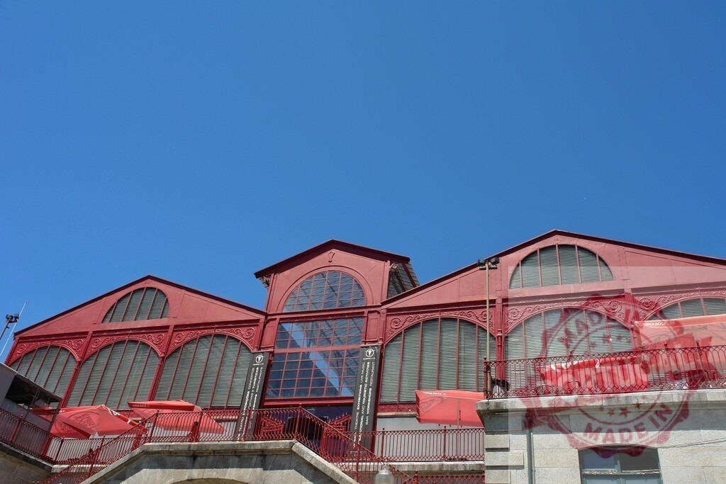 Mercado Ferreira Borges red iron architecture with blue sky in Porto. Porto - Portugal | Mercado Ferreira Borges building showcasing historical iron architecture under a clear blue sky - Realized with Pictrs.com