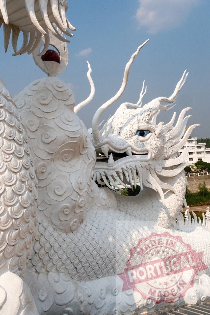 Majestic white dragon statue gazing under blue sky in Thailand | White dragon statue with blue eye gazing intensely, a symbol of power and good fortune in Thai culture - Realized with Pictrs.com