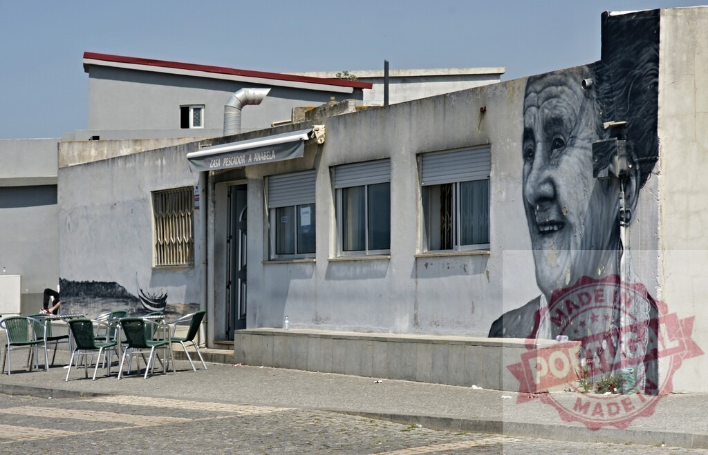 Aveiro Region - Portugal Elderly woman street art portrait mural on Portuguese building | Mural of an elderly woman adorning the facade of a cafe building in Portugal - Realized with Pictrs.com