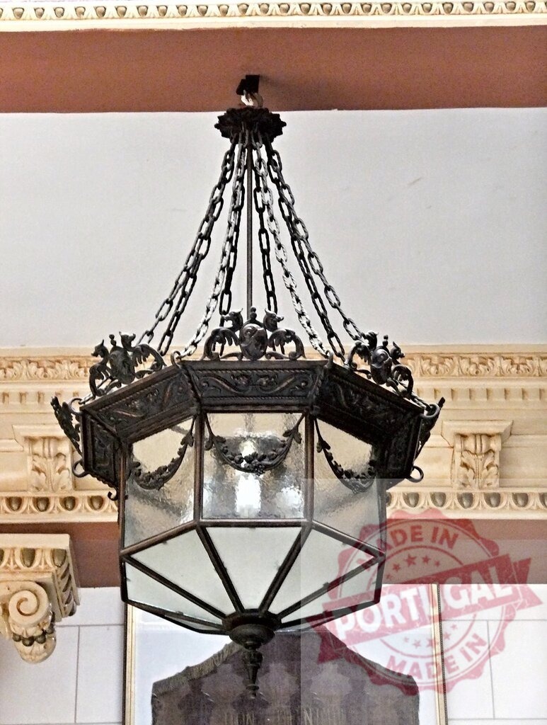 Antique ornate metal lantern hanging from ceiling chains | Ornate metal lantern hanging from a ceiling with decorative architectural details - Realized with Pictrs.com