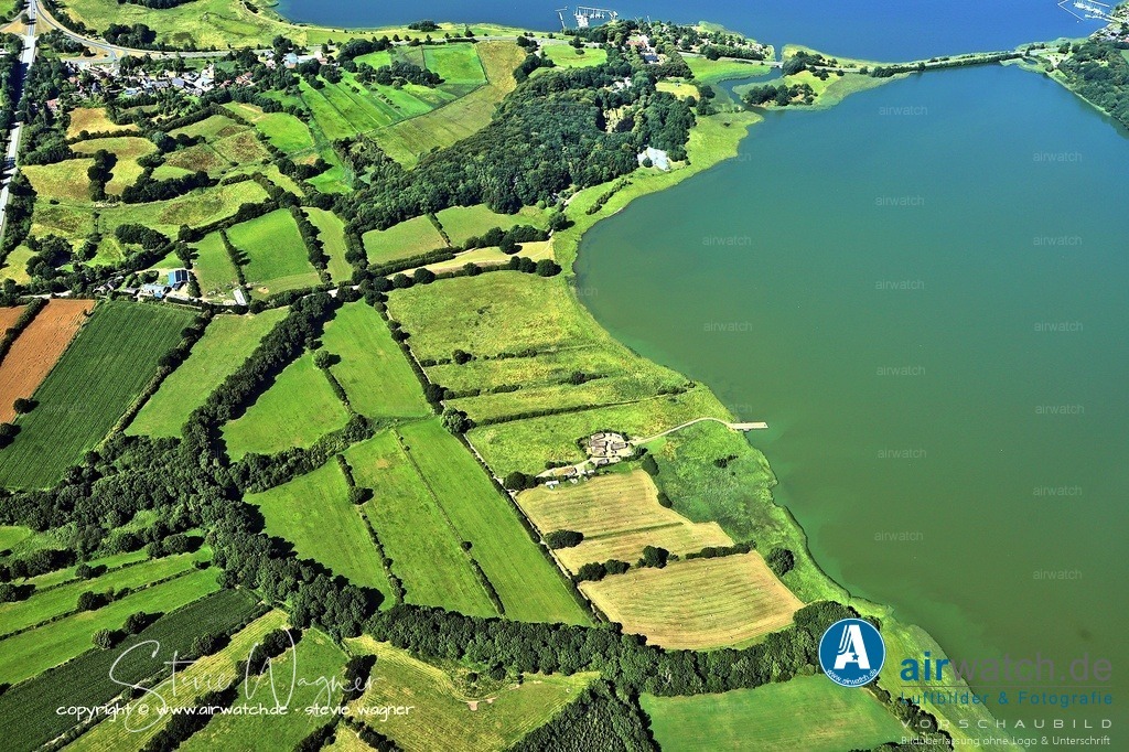 Haithabu - Die Stadt lag am Ende der Schlei - Luftbild | Die Stadt lag am Ende der Schlei, einem geschützten Meeresarm, der Schiffe aus dem Ostseeraum bis ins Landesinnere brachte.  Gleichzeitig war Haithabu direkt mit dem Danewerk, einer großen Grenzbefestigung, verbunden, was Schutz und politische Stabilität bot.  Der Ochsenweg, eine wichtige Nord-Süd-Landroute, führte in der Nähe vorbei und verband Haithabu mit weiteren Handelszentren.