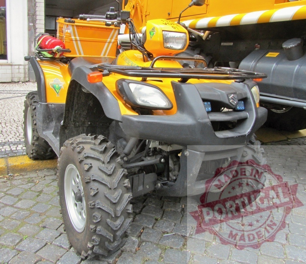 Suzuki ATV quad bike parked on cobblestones | Suzuki all-terrain vehicle in yellow and black parked on an urban street - Realized with Pictrs.com