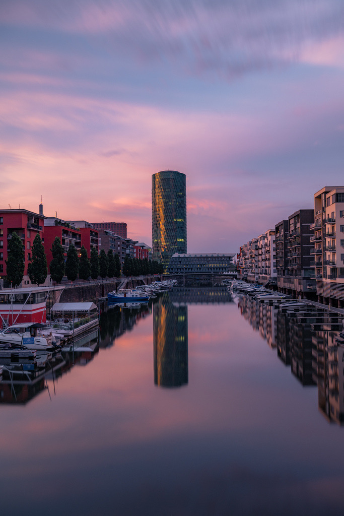 Westhafen Frankfurt zur blauen Stunde | Der Westhafen von Frankfurt spiegelt sich zur blauen Stunde im ruhigen Wasser. Moderne Architektur, klare Linien und sanfte Farbtöne prägen die urbane Szene. - Realisiert mit Pictrs.com
