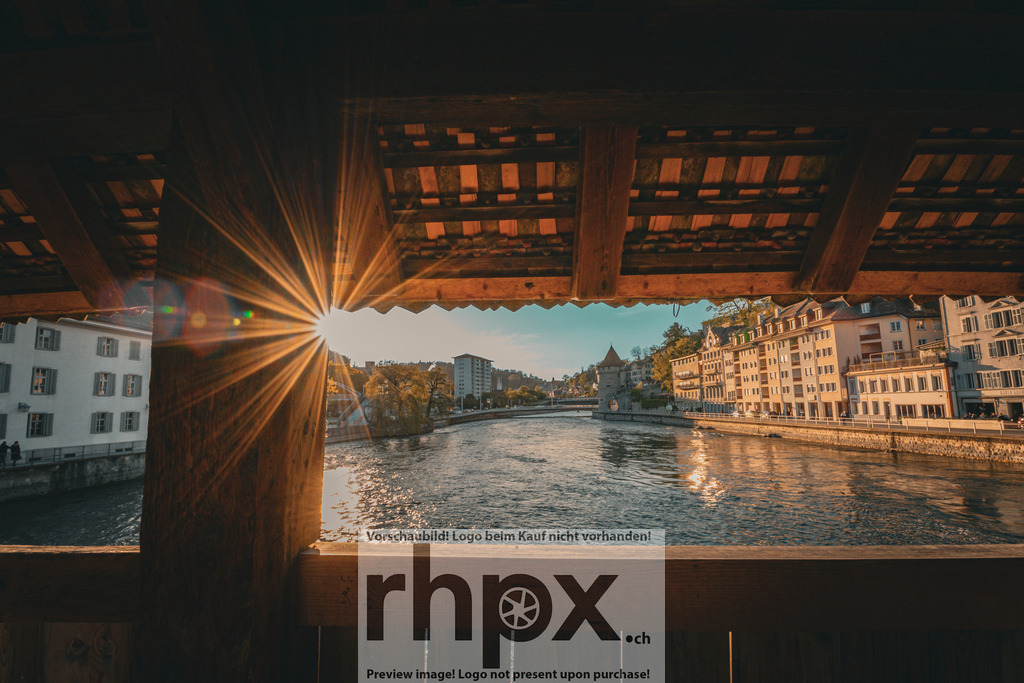 Sonnenstrahlen durch die Spreuerbrücke Luzern | Holz. Licht. Fluss.Die historischen Balken der Spreuerbrücke formen einen natürlichen Rahmen für dieses spektakuläre Lichtspiel. Der strahlende Sonnenstern durchbricht das Gebälk und taucht die Reuss sowie die Uferpromenade in einen hoffnungsvollen, goldenen Glanz.Wähle unter "Produktauswahl" dein Wunschformat: Vom klassischen Wandbild über Puzzle &amp; Tassen bis zum digitalen Download (z.B. als Handy-Hintergrund). - Realisiert mit Pictrs.com