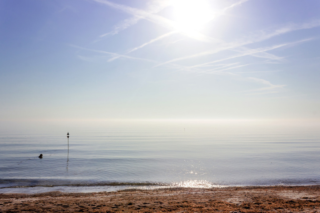 Wandbild: Küstenstille – Sanfter Morgen am Meer | Erleben Sie einen Moment vollkommener Ruhe an der Ostsee. Dieses maritime Wandbild fängt die friedliche Stimmung eines stillen Morgens am Strand ein, wenn das Wasser spiegelglatt liegt und die Sonne den Horizont in ein sanftes Licht taucht. Ein feiner Akzent im Wasser setzt einen dezenten Ankerpunkt für das Auge, während die weite Uferlinie für pure Entspannung sorgt. Ein ideales Motiv für das Wohnzimmer, das Klarheit und nordische Gelassenheit in Ihre Räume bringt – ein echtes Fenster zum Meer. - Realisiert mit Pictrs.com