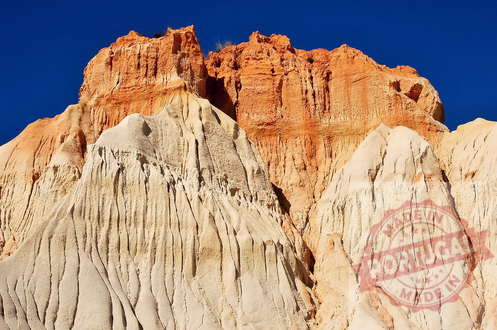 Algarve sandstone cliffs showing beautiful erosion patterns | Sandstone cliffs revealing intricate erosion patterns under a vibrant blue sky in the Algarve - Realized with Pictrs.com