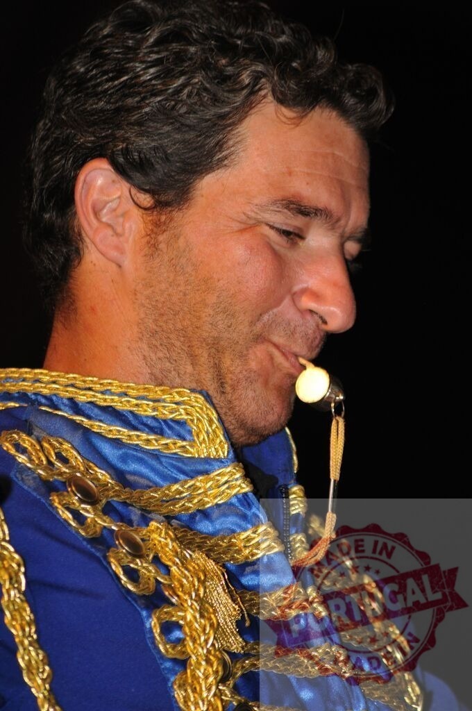 Man playing whistle in blue gold band uniform | Musician in a decorated uniform playing a metal whistle against a dark background - Realized with Pictrs.com