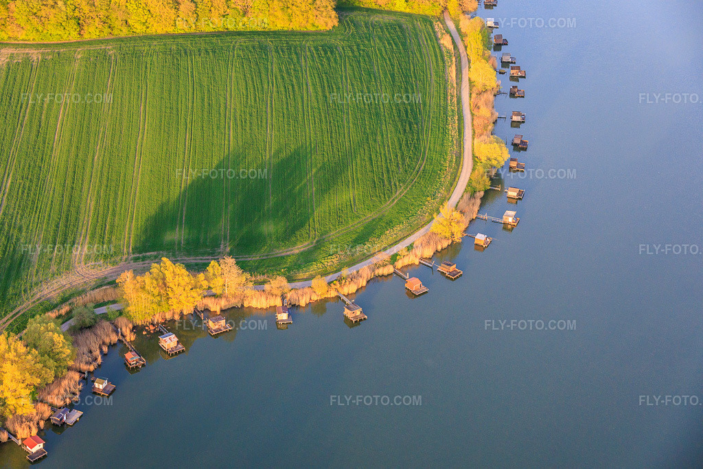 Aerial view: Boardwalks with fishing huts line the shore of Lake Etang du Welschhof. in Puttelange-aux-Lacs in the state Moselle, France. – Photo: IMG_154806.jpg taken on 04/17/2026 by Werner Riehm/FLY-FOTO.com – Resolution of the original: 6000 x 4000 px