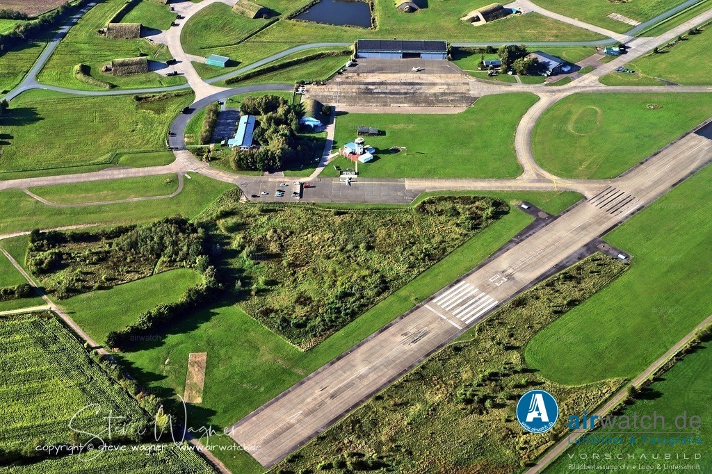 Luftbild Flughafen Husum-Schwesing - Die Start- und Landebahn ist in zwei Teile unterteilt | Die Start- und Landebahn ist in zwei Teile unterteilt: Der südwestliche Teil ist für die zivile Nutzung bestimmt, während der nordöstliche Teil weiterhin von der Bundeswehr genutzt wird. Die Hauptstartbahn (RWY 03/21) hat eine Länge von 1.450 Metern und eine Breite von 30 Metern, mit einem Asphaltbelag und einem Betonkopf am Startende der Bahn 03.