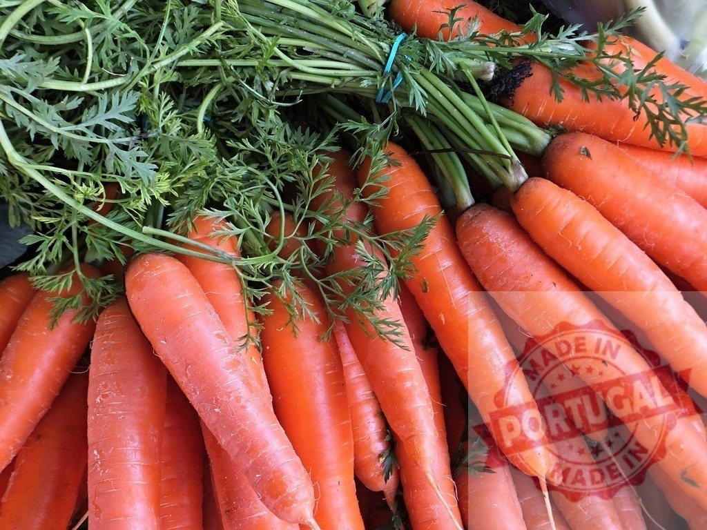 Fresh organic carrots with green tops at market | Bunches of fresh organic carrots showing green leafy tops harvested for sale - Realized with Pictrs.com