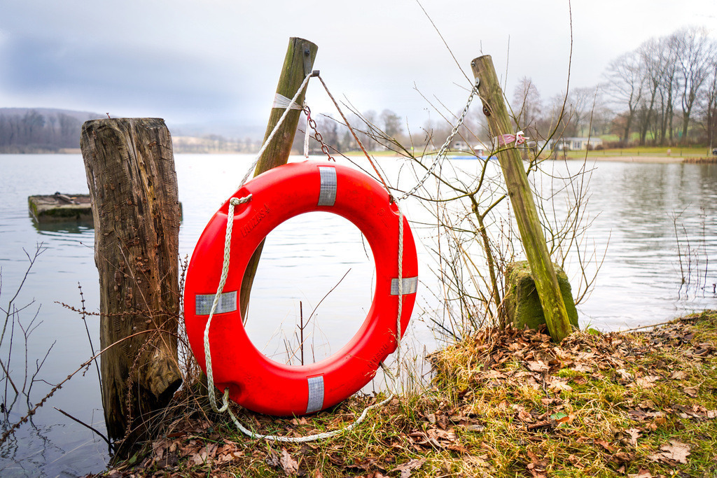 Einsamer Retter - Gedern | Der Gederner See liegt wie eine stille Oase im Winterschlaf. Wo sonst der Lärm planschender Kinder die Umgebung füllt, hält abseits der Badesaison die Zeit an. Als Spiegelbild des grauen Himmels breitet sich die Wasseroberfläche vor den sporadischen Besuchern aus. Die Natur hält den Atem an und wartet reglos auf das kommende Erwachen. Denn selbst im tiefsten Winter schlummert unter der gläsernen Oberfläche bereits das Versprechen eines neuen Frühlings. - Realisiert mit Pictrs.com