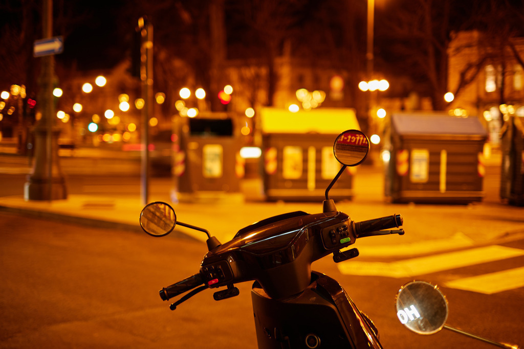 abgestelltes Moped mit Blick auf die Strasse | Triest, Austria - March 10, 2022: abgestelltes Moped mit Blick auf die Strasse in der Nacht. - Realisiert mit Pictrs.com