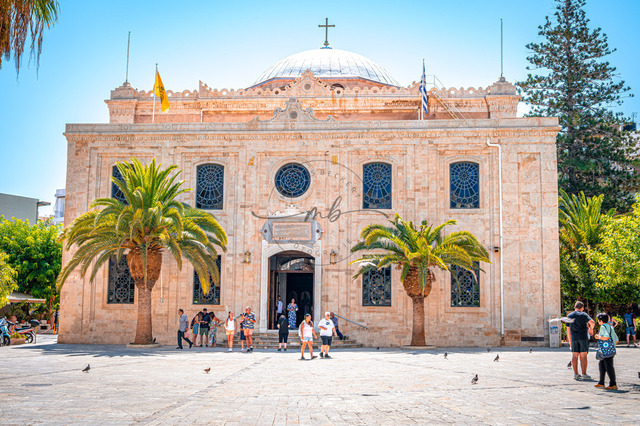 2026-07-20_10-36-18_920 | Historische Kirche mit Palmen auf einem sonnigen Platz, umgeben von Menschen und mediterranem Flair, Heraklion, Kreta, Griechenland - Realisiert mit Pictrs.com