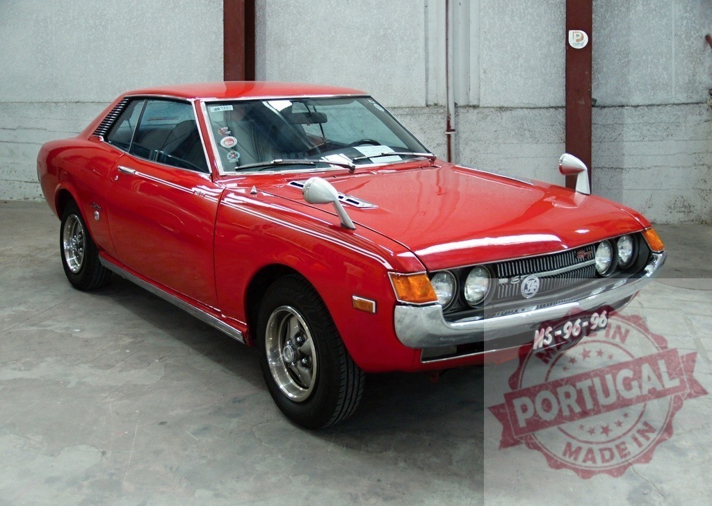 Red Toyota Celica parked in garage is shining and waiting | Classic red Toyota Celica coupe parked in garage, with fender mirrors - Realisiert mit Pictrs.com