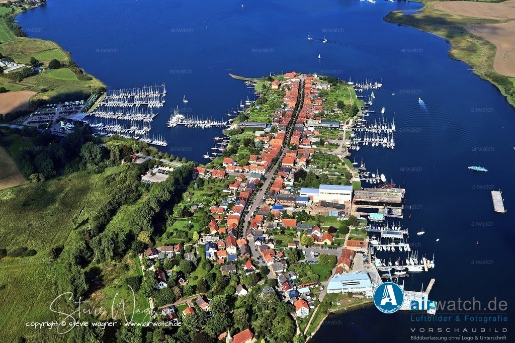 Luftbild Ostseefjord Schlei, Stadt Arnis - kleinste Stadt Deutschlands - Perle an der Schlei | Heute ist Arnis ein beliebtes Ausflugsziel, bekannt für seine idyllische Lage, weiß gestrichenen Altbauten mit roten Ziegeldächern, bunt gestrichenen Türen und reich verzierten Fassaden. Der Ort verfügt über keine eigene Verwaltung, kein Postamt oder Supermarkt. Besucher parken außerhalb und erkunden die Stadt zu Fuß. Eine Schleifähre verbindet Arnis im Sommerhalbjahr mit Sundsacker.