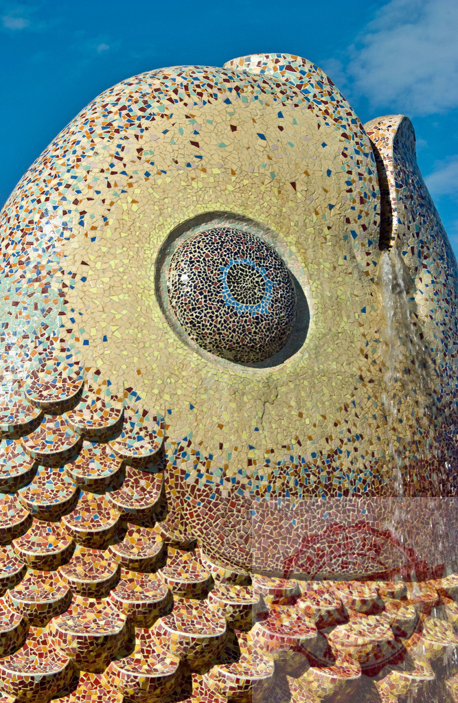 Mosaic fish sculpture fountain with blue sky background | Close-up of a colorful mosaic fish sculpture and fountain displaying intricate scales and eye detail - Realisiert mit Pictrs.com