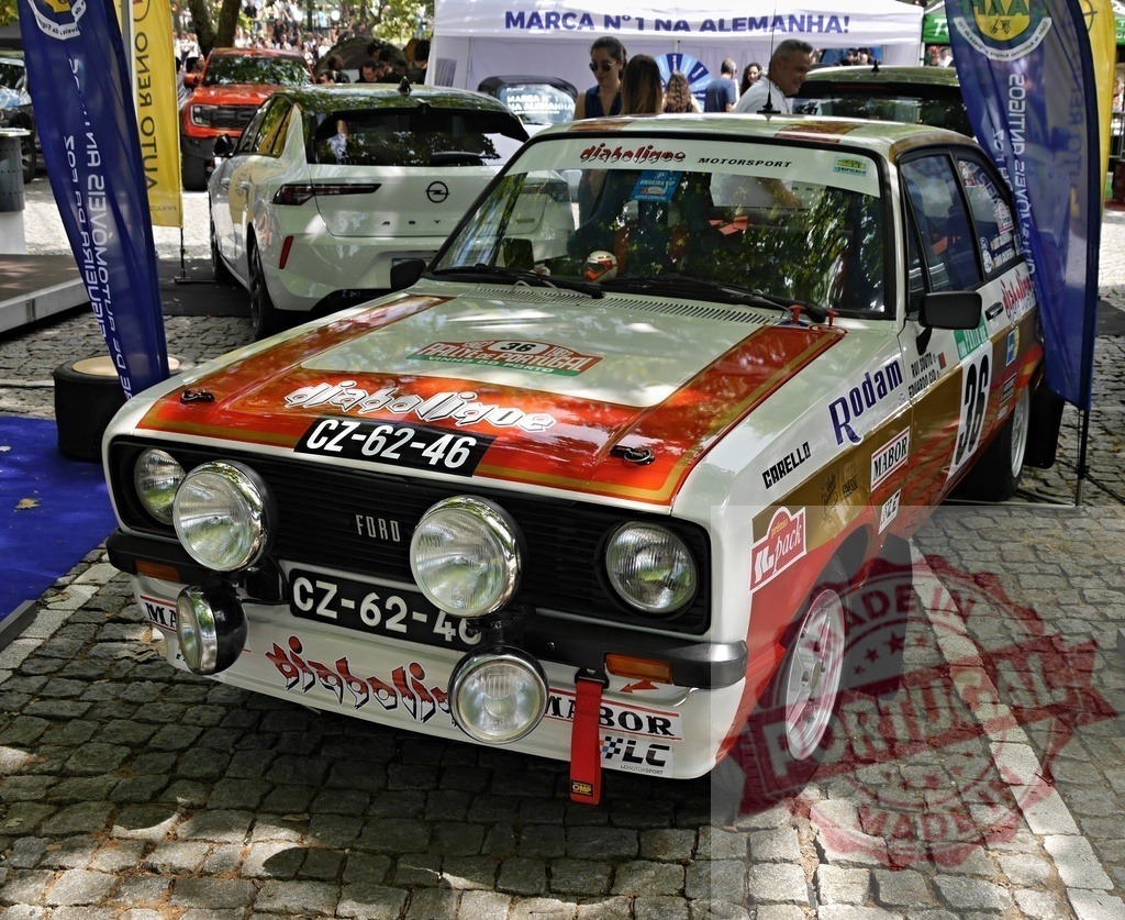 Ford Escort Mk2 rally car parked at car show event | Classic Ford Escort Mk2 rally car with racing livery displayed outdoors on cobblestones - Realisiert mit Pictrs.com