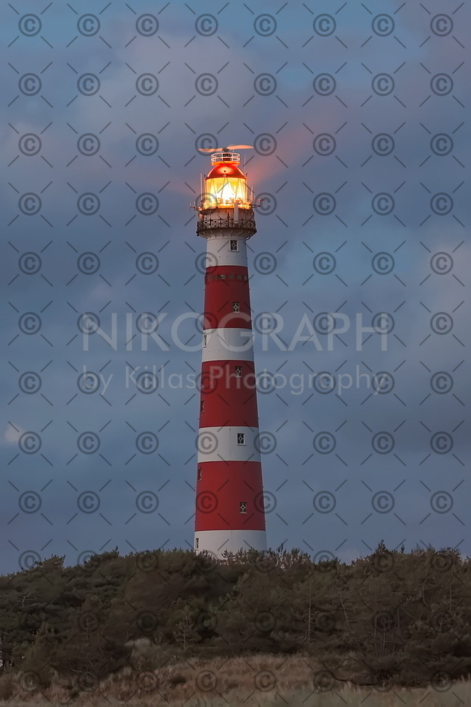 Abendstimmung am Leuchtturm Ameland | Die Wolken leuchten vom Licht der Abendsonne rot auf und betten den Leuchtturm von Ameland in eine dramatische Szene ein. Der Leuchtturm von Ameland wurde 1880 gebaut und ist rund 55 Meter hoch. Der Leuchtturm besteht aus 15 Gusseisernen Segmenten, welche nach Ameland verschifft und vor Ort zusammengebaut wurden. Die Optik des Leuchtturmes sorgt alle 15 Sekunden für drei Blitze, die über 50 km weit zu sehen sind. 

Bestellen Sie ein Ameland-Bild direkt als Leinwandbild für Ihr Wohnzimmer, als Acrylglasbild für Ihre Küche oder als Alu-Dibond-Bild für Ihre Aussenwand. Wie wäre es mit einem Puzzle oder einem Glasschneidebrett mit einem Photomotiv aus Ameland?