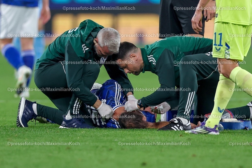 S0401082501136 | 01.08.2025, Fußball, FC Schalke 04 - Hertha BSC, 1.Spieltag, 2. Fußball Bundesliga, Veltins-Arena Gelsenkirchen, Saison 2025 2026: Nikola Katic (Schalke04 #25) liegt verletzt am Boden und muss mit einer Verletzung am Kopf Ohr behandelt werden DFB regulations prohibit any use of photographs as image sequences and or quasi-video.