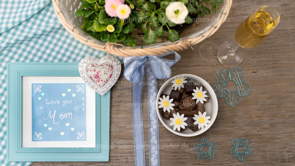 Mother's Day with small presents photographed from above | Muttertag mit kleinen Geschenken, von oben fotografiert. Ein Bilderrahmen enthält ein Lettering mit englischem Text: love you mom. Muttertagsmotiv. 