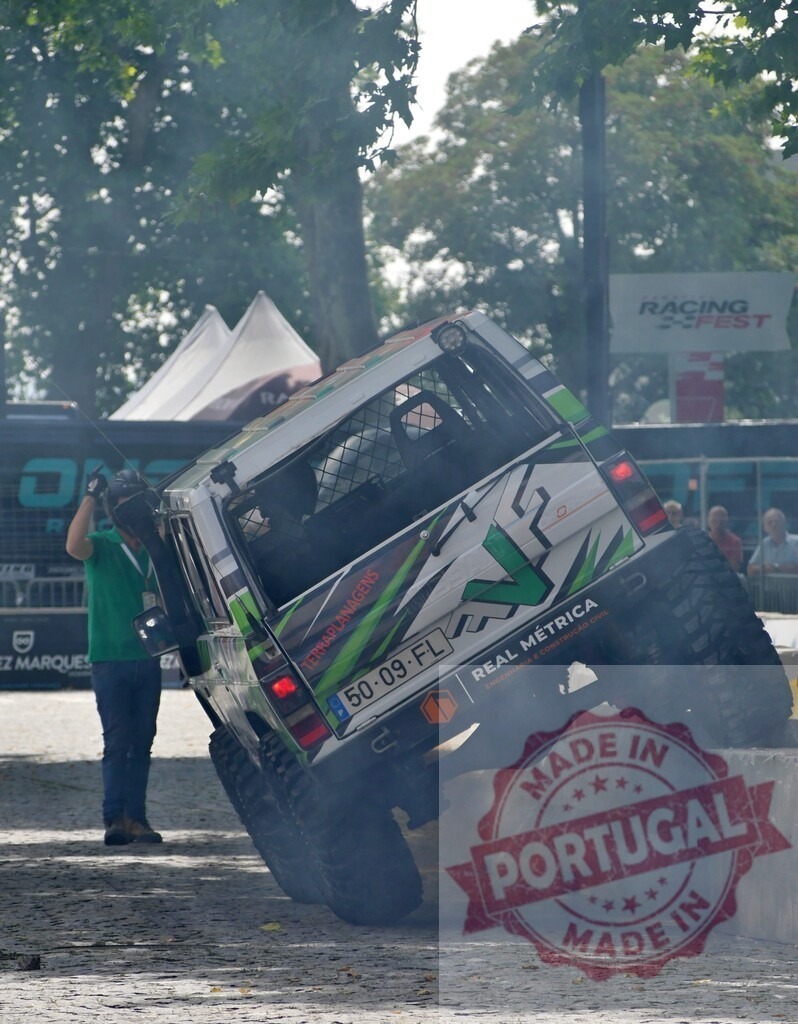 Offroad car climbing concrete block at racing festival | Offroad car climbing a concrete block at a racing festival, emitting smoke from tires - Realisiert mit Pictrs.com