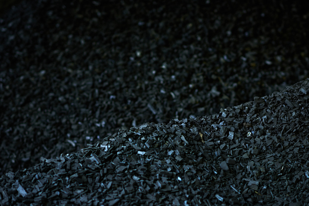 Detail auf dem Kohlplatz | Michelbach, Austria - May 08, 2019: Waldköhlerei Hochecker, die 2011 in das Nationale Verzeichnis des immateriellen Kulturerbes der UNESCO aufgenommen wurde, produziert noch echte Holzkohle; gehäufte Kohle in der Kohlehalle. - Realisiert mit Pictrs.com