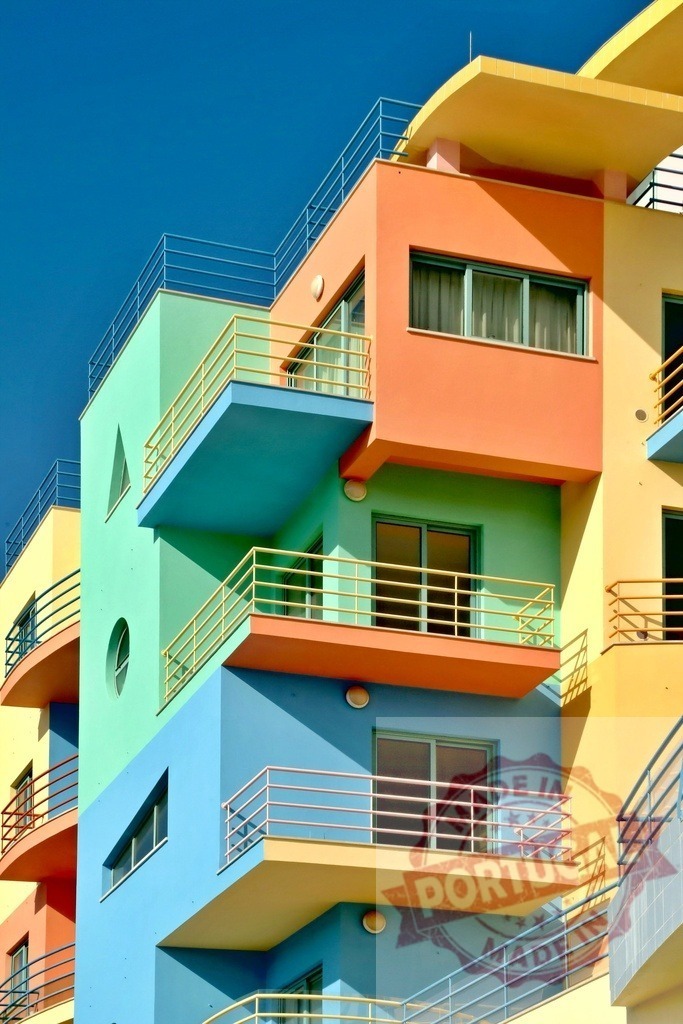 Colorful residential building featuring postmodern geometric style architecture | Multicolored facade with balconies and windows contrasting against a clear blue sky - Realized with Pictrs.com