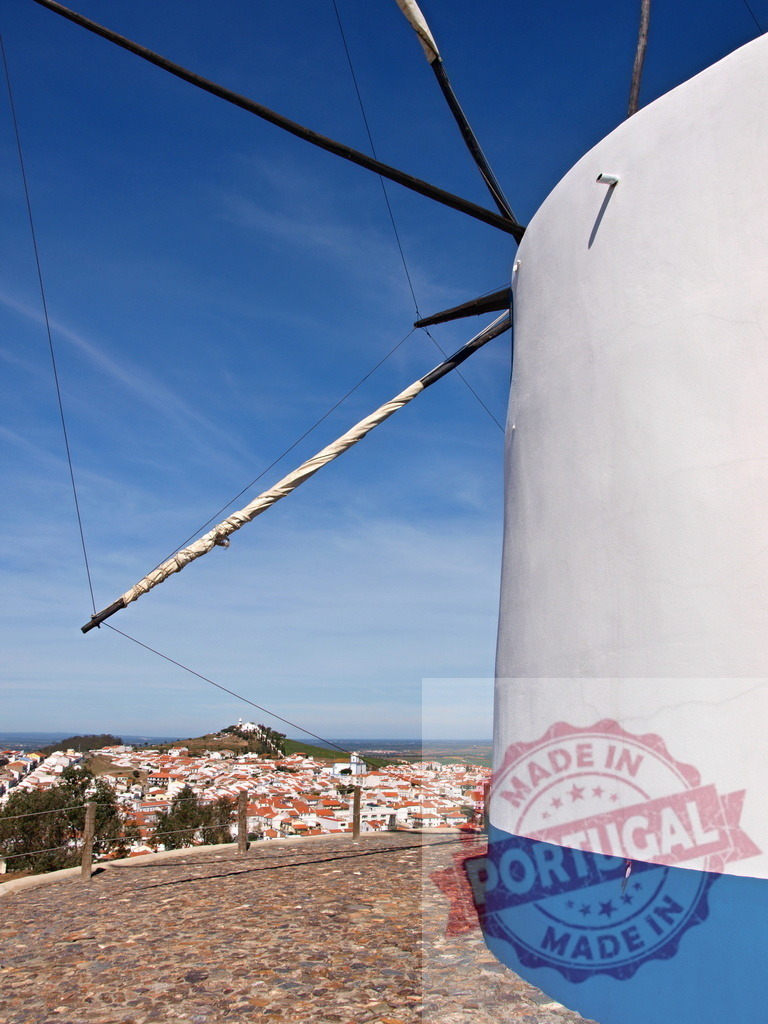 Traditional windmill overlooking village in Portugal Alentejo | Traditional windmill standing above a whitewashed village under blue sky in Alentejo, Portugal - Realisiert mit Pictrs.com