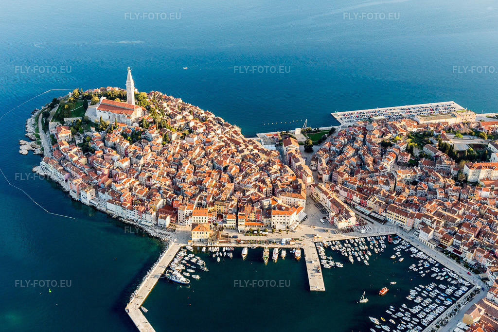 Vue aérienne: Vue de la ville sur la côte méditerranéenne près de la vieille ville de Rovinj en Istarska Župania - Istrie, Croatie. Le promontoire proéminent se situe sur la côte ouest de la péninsule istrienne. à Rovinj dans le département Gespanschaft Istrien, Croatie. Photo: IMG_106281.jpg prise le 14/04/2018 par Werner Riehm/FLY-FOTO.eu – Résolution de l'original: 5340 x 3560 px