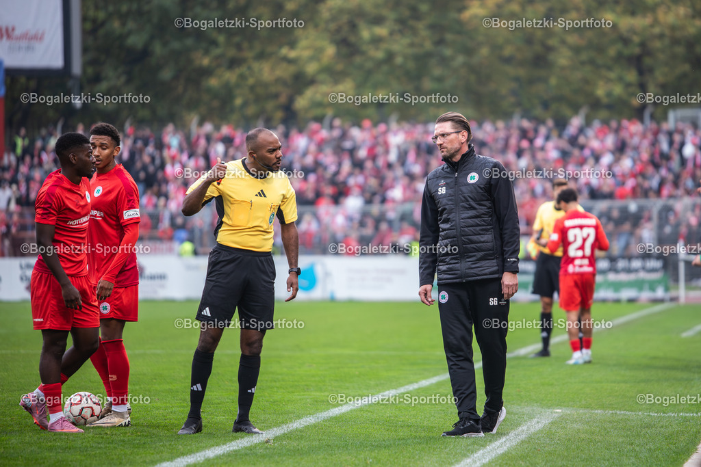 Schiedsrichter Jonah Besong | 11.10.2025, Fußball, Niederrheinpokal, Rot-Weiß Oberhausen - Rot-Weiss Essen: Schiedsrichter Jonah Besong ermahnt die Oberhausener Bank. Daneben stehen RWO-Trainer Sebastian Gunkel, Eric Gueye (Rot-Weiß Oberhausen #11, zweiter von Links) und Burinyuy Nyuydine (Rot-Weiß Oberhausen #19, ganz Links)  - Realisiert mit Pictrs.com
