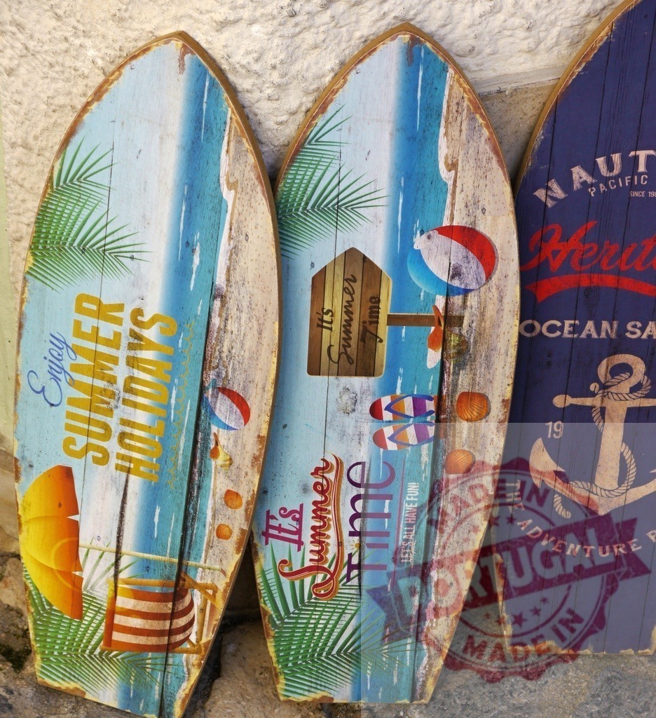 Vintage wooden surfboards decorating a wall for summer | Vintage wooden surfboards with summer holiday themed decorations standing on a stone wall - Realized with Pictrs.com