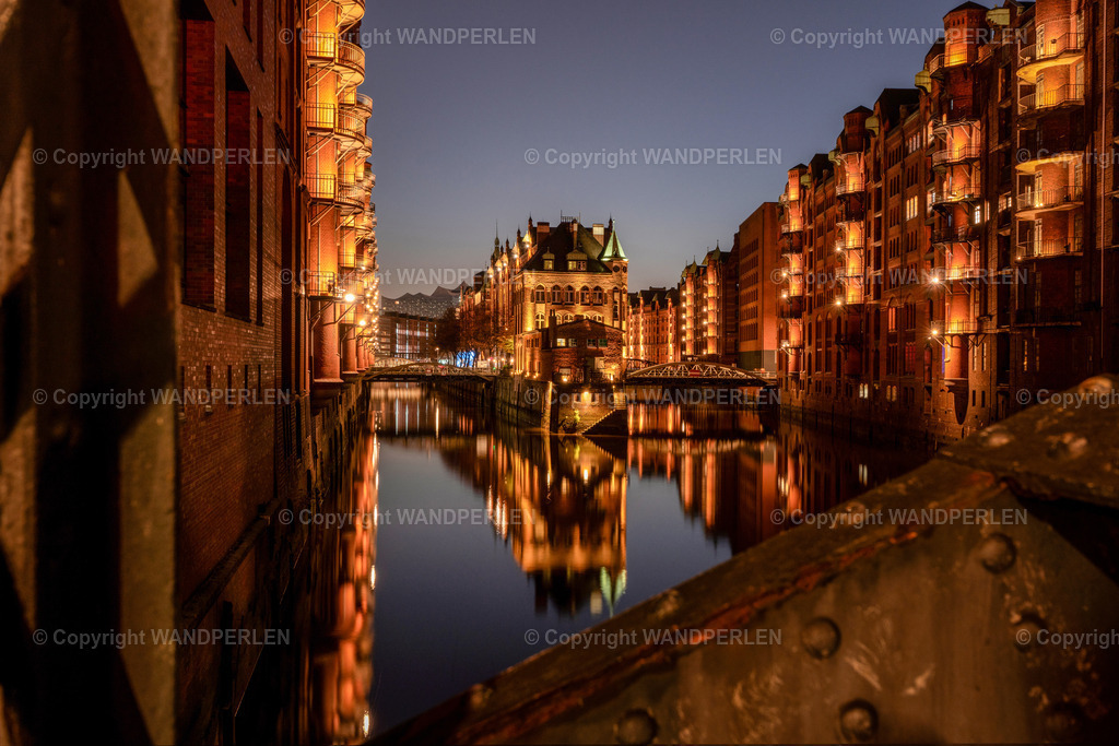 Wandrahmfleet mit dem Wasserschlößchen | Hamburgs Speicherstadt erstrahlt bei Nacht in warmem Licht, Die charakteristischen roten Backsteingebäude an den Fleeten spiegeln sich im ruhigen Wasser. - Realisiert mit Pictrs.com
