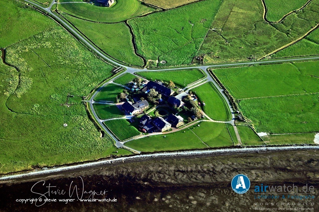 Auf der Hallig Oland existiert nur eine einzige Warft - Luftbild Hallig Oland | Auf der Hallig Oland existiert nur eine einzige Warft, die als Olandwarft bezeichnet wird. - Dieser künstlich aufgeschüttete Hügel beherbergt mehrere Häuser, die eng aneinanderschmiegen, und schützt die Bewohner vor den regelmäßigen Überflutungen der Nordsee. Die Warft wurde in den Jahren 1967 und 1968 auf eine Höhe von 5,25 Metern über Normalnull erhöht, nachdem schwere Sturmfluten massive Schäden verursacht hatten.