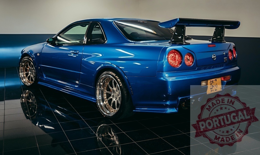 Nissan Skyline GT-R R34 blue sports car parked indoors | Blue Nissan Skyline GT-R R34 sports car showcasing tuning modifications and rear view - Realisiert mit Pictrs.com