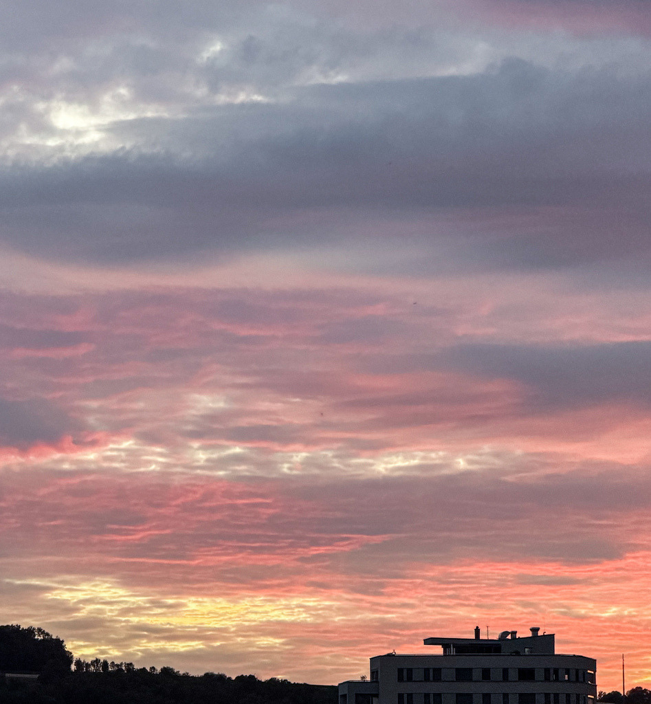 Wandbild Malerisches Abendrot - Romantischer Wolkenhimmel über der Stadt | Dieses emotionale Fine-Art-Wandbild fängt die magische Stimmung eines intensiven Abendrots in meisterhafter Farbbrillanz ein. Das dramatische Zusammenspiel aus glühenden Orange-, warmen Rosa- und tiefen Violetttönen verwandelt den Wolkenhimmel in ein lebendiges Naturschauspiel über den sanften Silhouetten der Stadt. Fotograf Robert Steinke fängt diese friedvolle und zugleich kraftvolle Atmosphäre in gestochen scharfer Premium-Qualität ein. Ein wunderschöner, harmonischer Blickfang für das Wohnzimmer, Schlafbereiche oder Wellnesszonen, der sofort Wärme, Geborgenheit und stilvolle Eleganz ausstrahlt. Perfekt geeignet als großformatiger Premium-Kunstdruck auf Leinwand, edlem Alu-Dibond oder unter brillantem Acrylglas für maximale Tiefenwirkung. - Realisiert mit Pictrs.com