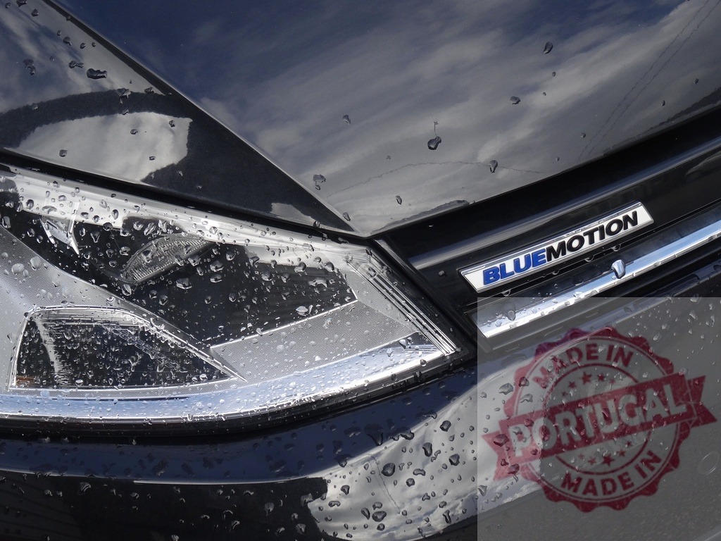 Volkswagen Bluemotion car headlight with raindrops | Volkswagen Bluemotion car front showing headlight and hood with many raindrops - Realized with Pictrs.com
