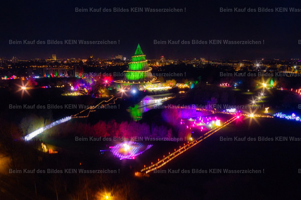 lumagica_Magdeburg_Jahrtausendturm_Nachts_0023 | Diese stimmungsvolle Luftaufnahme zeigt den Jahrtausendturm während der Lichtausstellung **Lumagica** im Elbauenpark. Farbenfrohe Lichtinstallationen und kunstvoll illuminierte Wege verwandeln den Park in eine faszinierende Erlebniswelt. Der angestrahlte Jahrtausendturm bildet den Mittelpunkt der Szenerie und setzt sich eindrucksvoll von der nächtlichen Umgebung ab. Erst aus der Luft wird sichtbar, wie harmonisch sich die Lichtkunst in die Parklandschaft einfügt.Mit **Lumagica** hat sich der Elbauenpark in den Wintermonaten zu einem beliebten Ausflugsziel entwickelt. Tausende Besucher erleben jedes Jahr die aufwendig gestalteten Lichtinstallationen, die den Park in eine märchenhafte Kulisse verwandeln. Der Jahrtausendturm bildet dabei das weithin sichtbare Wahrzeichen und sorgt gemeinsam mit den farbenfrohen Illuminationen für eine ganz besondere Atmosphäre.Diese Luftaufnahme verbindet moderne Lichtkunst mit einem der bekanntesten Wahrzeichen Magdeburgs. Sie zeigt den Elbauenpark einmal von einer völlig anderen Seite und macht deutlich, warum die Kombination aus Architektur, Natur und Lichtinszenierung Jahr für Jahr zahlreiche Besucher begeistert. - Realisiert mit Pictrs.com