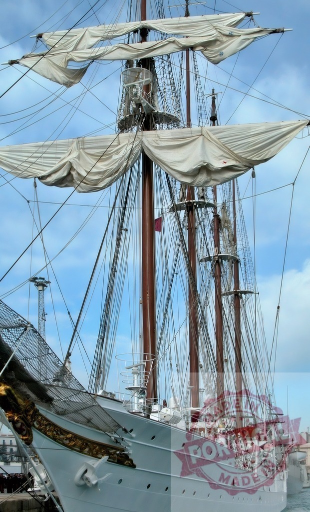 Historic tall ship docked a port with furled sails. Espana - Cadiz | Tall ship masts and rigging with furled sails against a blue sky - Realized with Pictrs.com