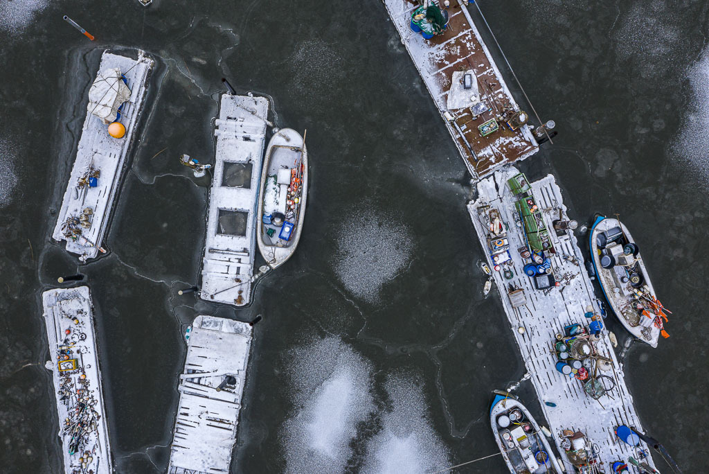 zeitenwende-farbe-01-06 | Im Eis der Schlei: Landungsbrücken und Boote in der Fischersiedlung Holm in Schleswig aus der Vogelperspektive - Realisiert mit Pictrs.com