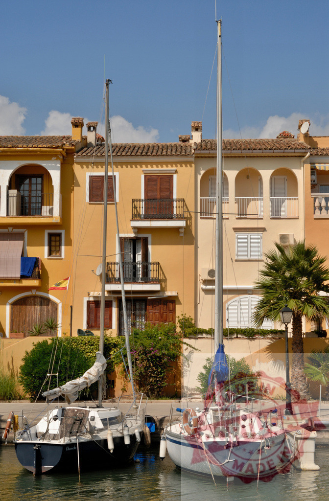 Sailboats mooring in front of colorful houses in Portocolom, Majorca | Two sailboats are moored in front of a row of colorful houses with balconies in Portocolom, Majorca, Spain - Realisiert mit Pictrs.com