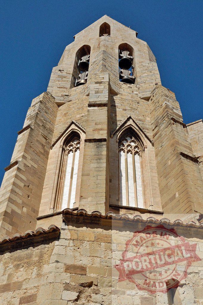 Sant Feliu church bell tower in Girona, Spain | Sant Feliu church bell tower showing gothic architecture details and bells against blue sky - Realized with Pictrs.com